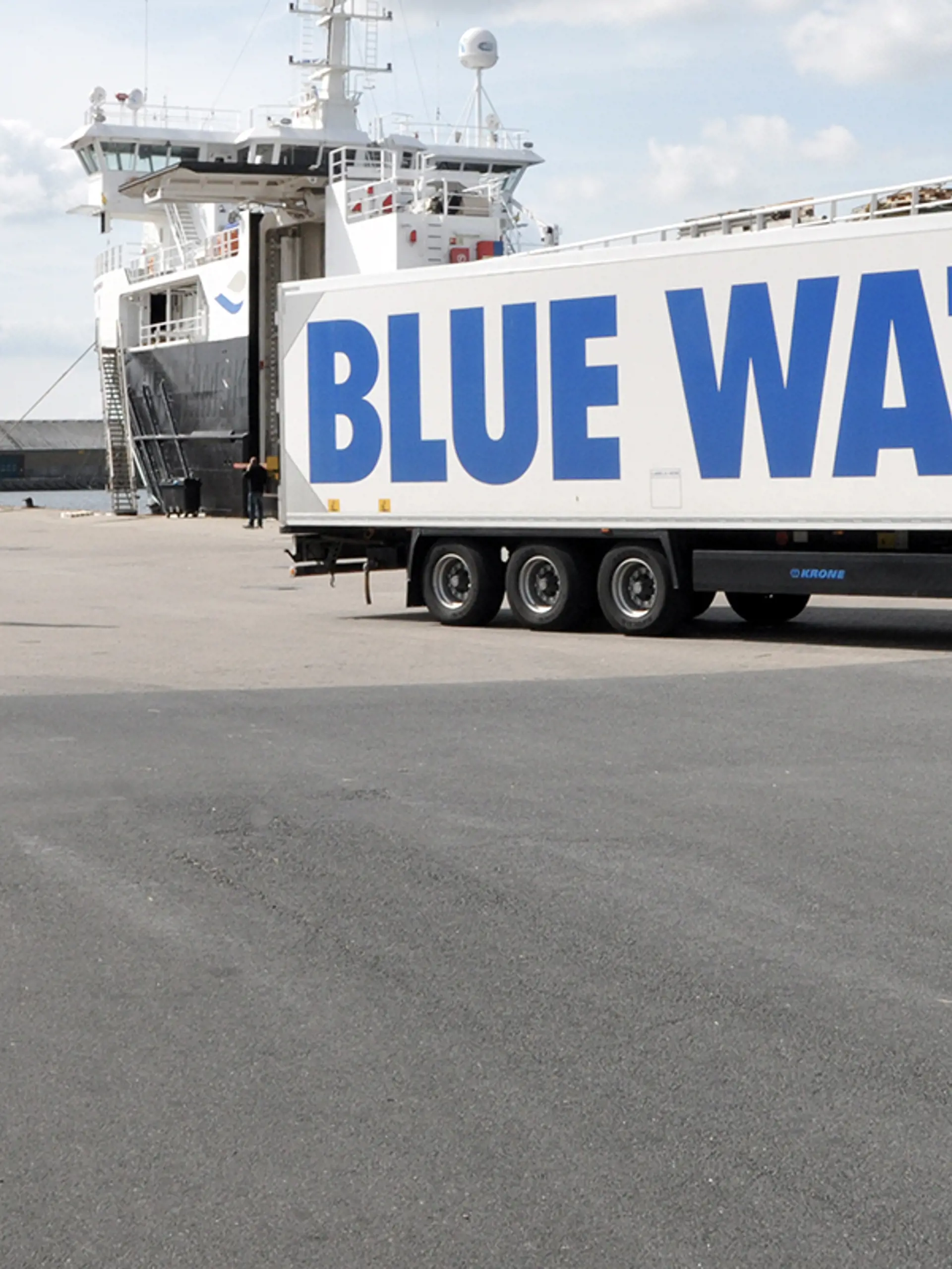 Man walking next to a Blue Water Shipping truck at the Harbour of Singapore